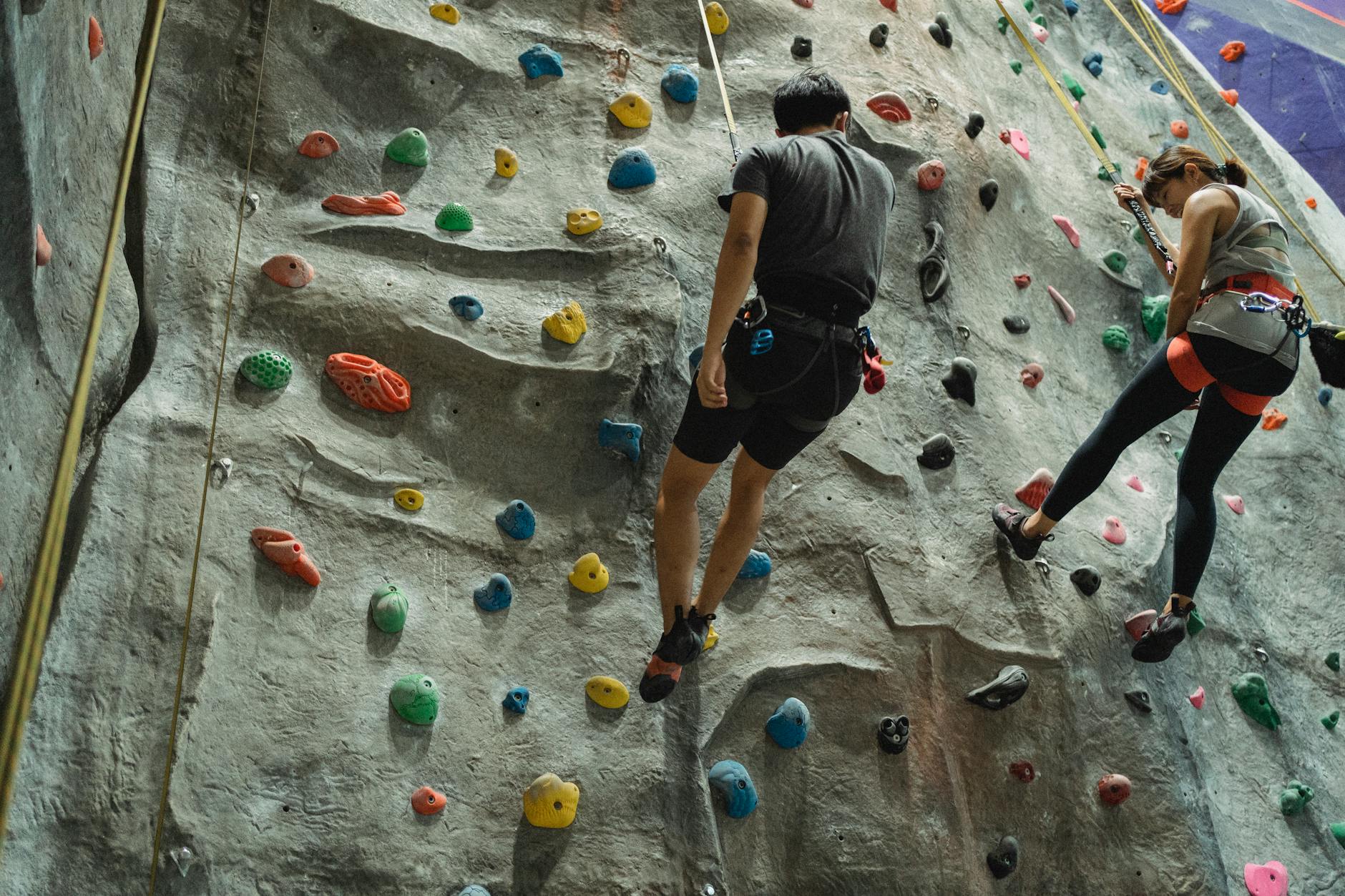 Climber ascending a vertical rock face in a desert environment