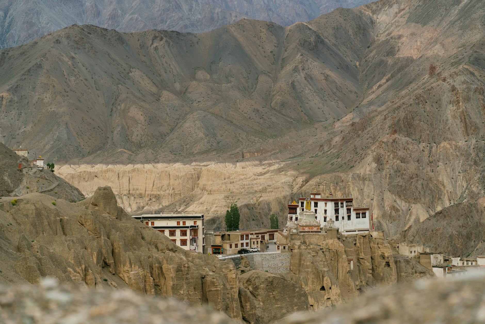 Ancient Buddhist monastery built into red rock cliffs in a high-altitude Himalayan landscape