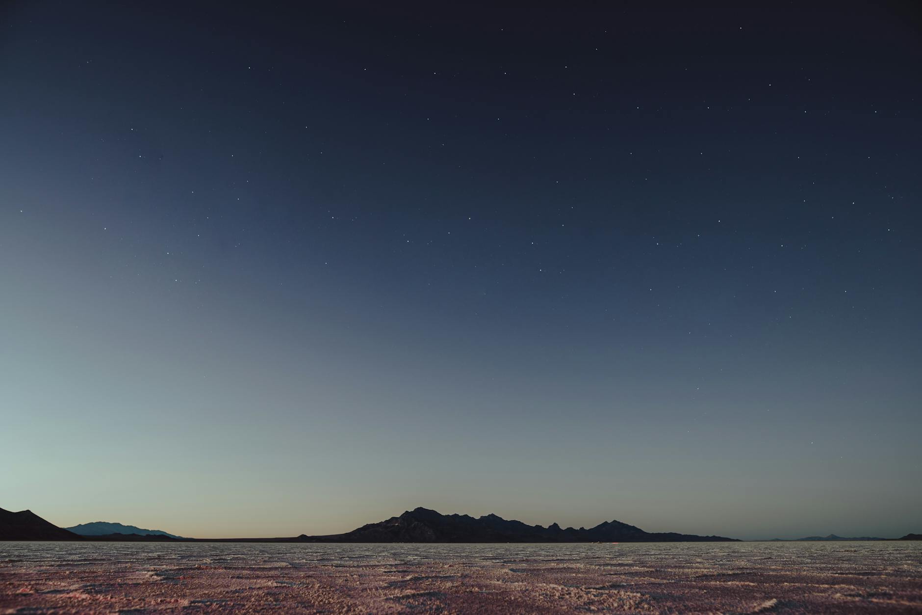 A wide-angle view of a clear night sky filled with stars above a quiet desert campsite