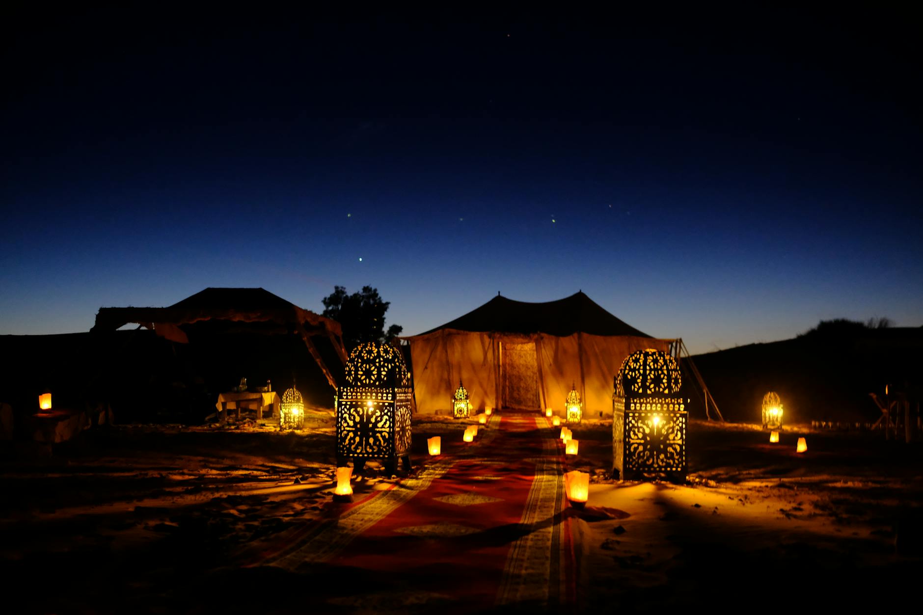 Bedouin-style desert camp at night with stars visible above the sand dunes