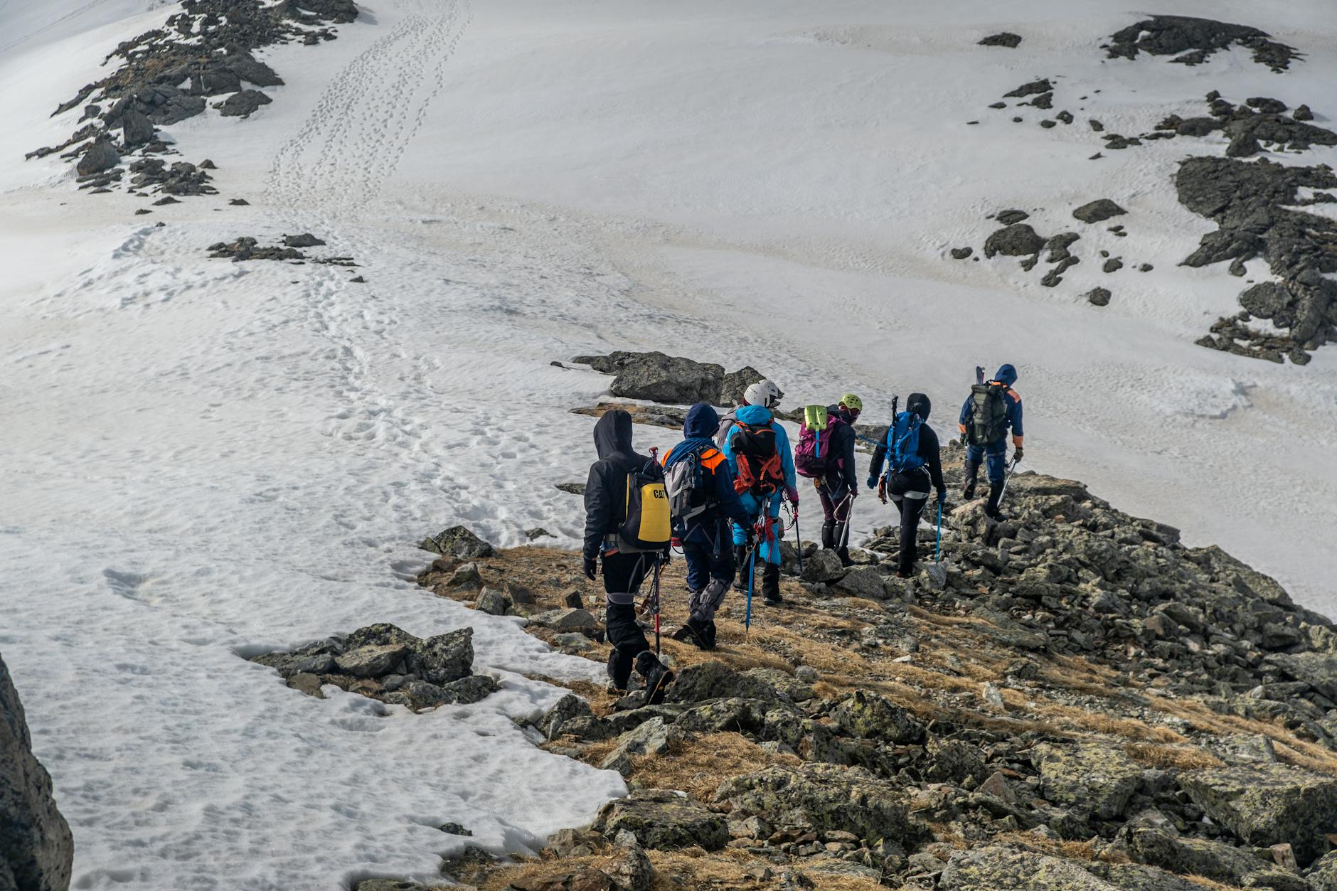 Solo trekker walking along a high-altitude mountain trail with a heavy backpack