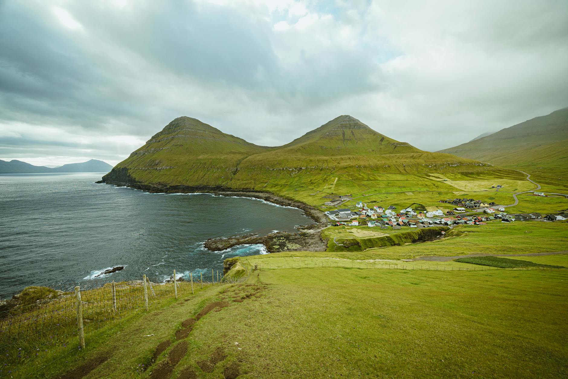 A small coastal Nordic village nestled at the foot of steep mountains beside a fjord