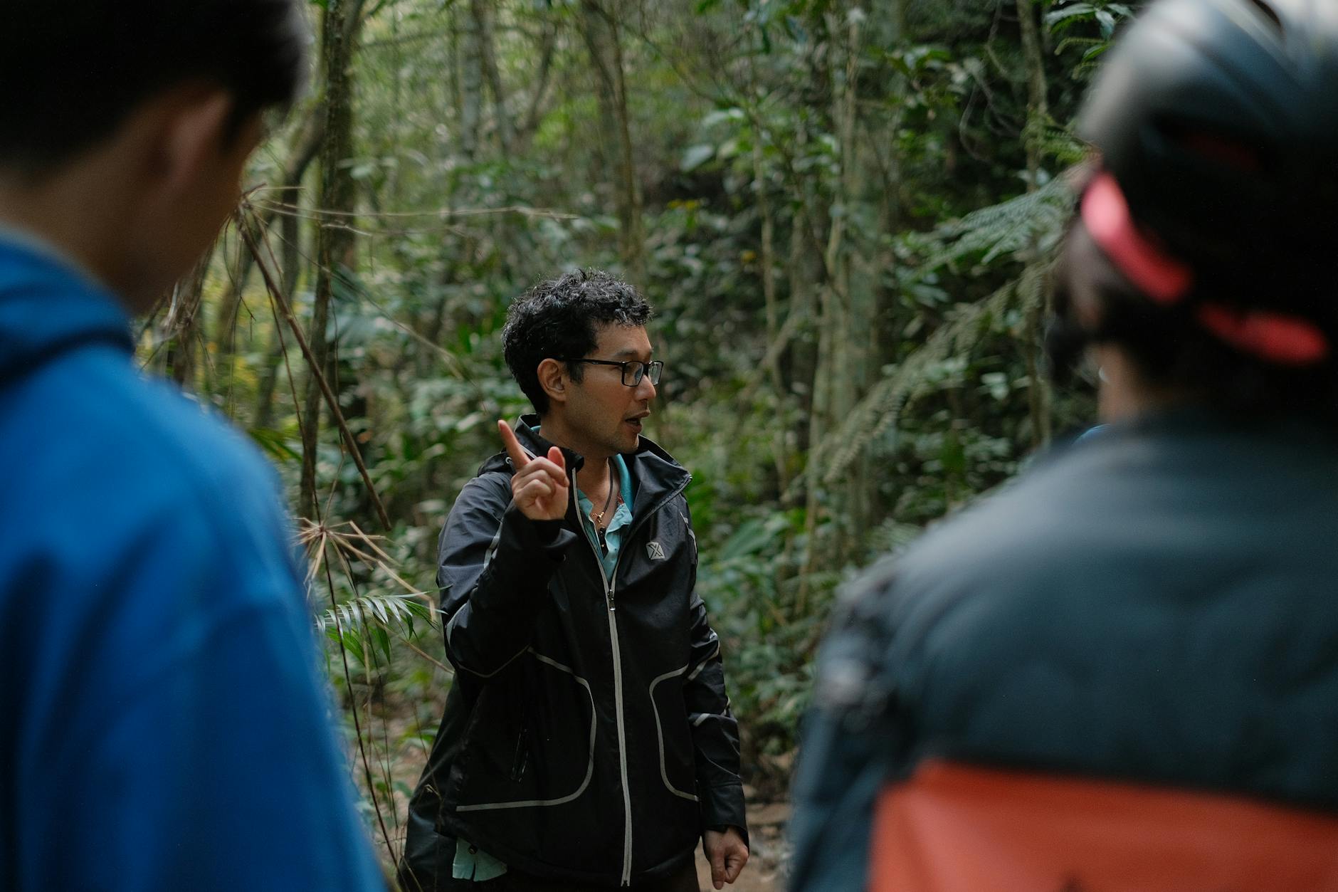 A local guide leading a small group of travelers through a dark forested trail at night