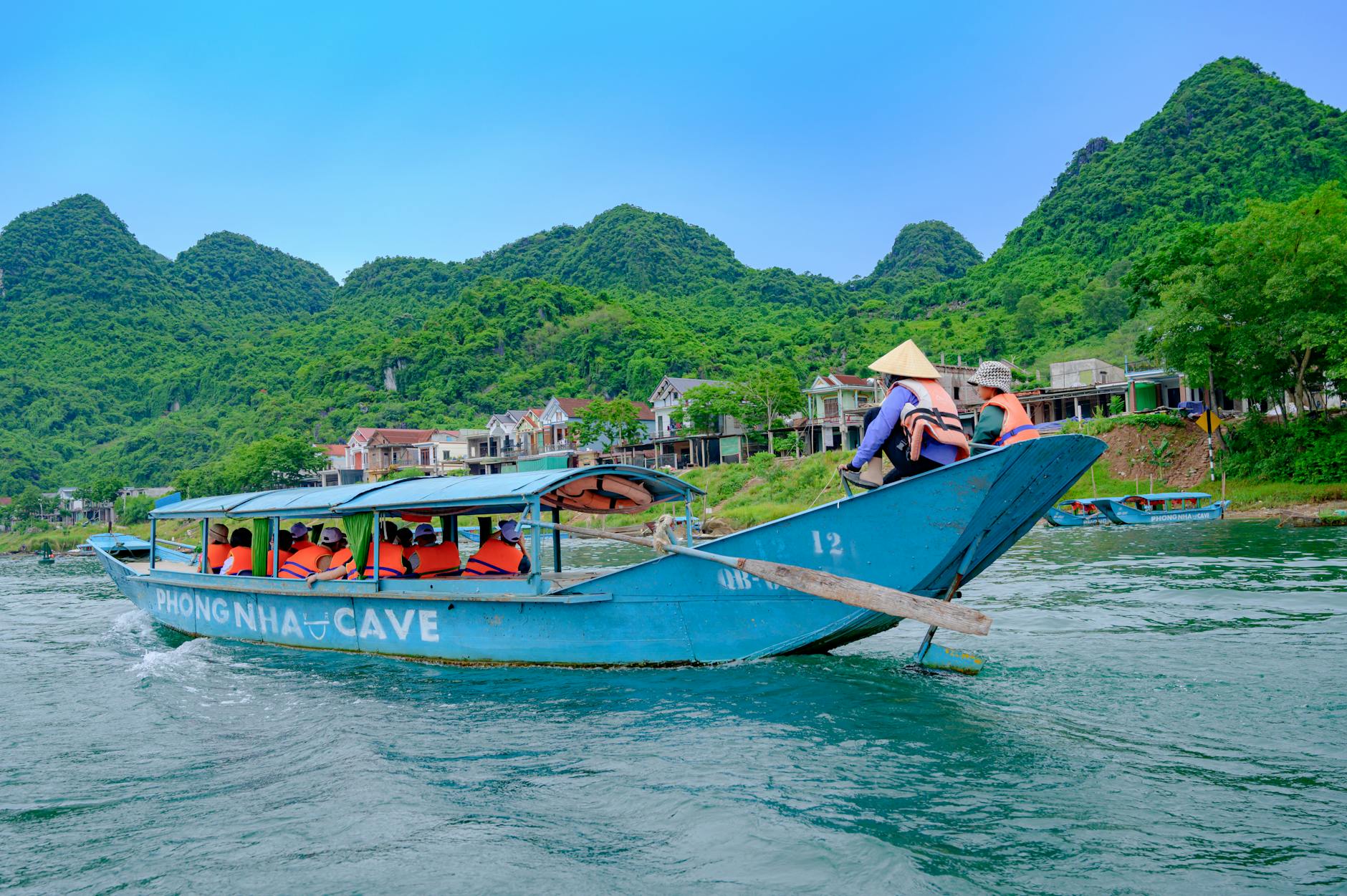 Traditional wooden boat navigating narrow canal waterway in rural Vietnam