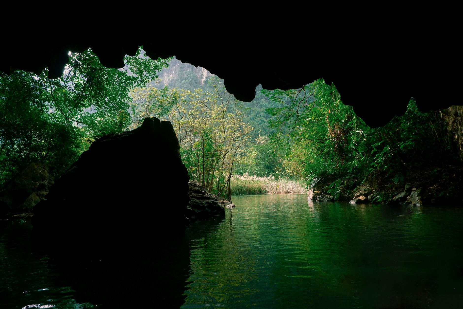 Dramatic limestone karst formations rising above a calm river valley in northern Laos