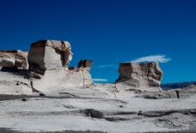Pale chalk rock formations rising from flat sand in Egypt's White Desert national park
