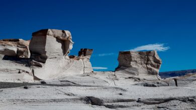 Pale chalk rock formations rising from flat sand in Egypt's White Desert national park