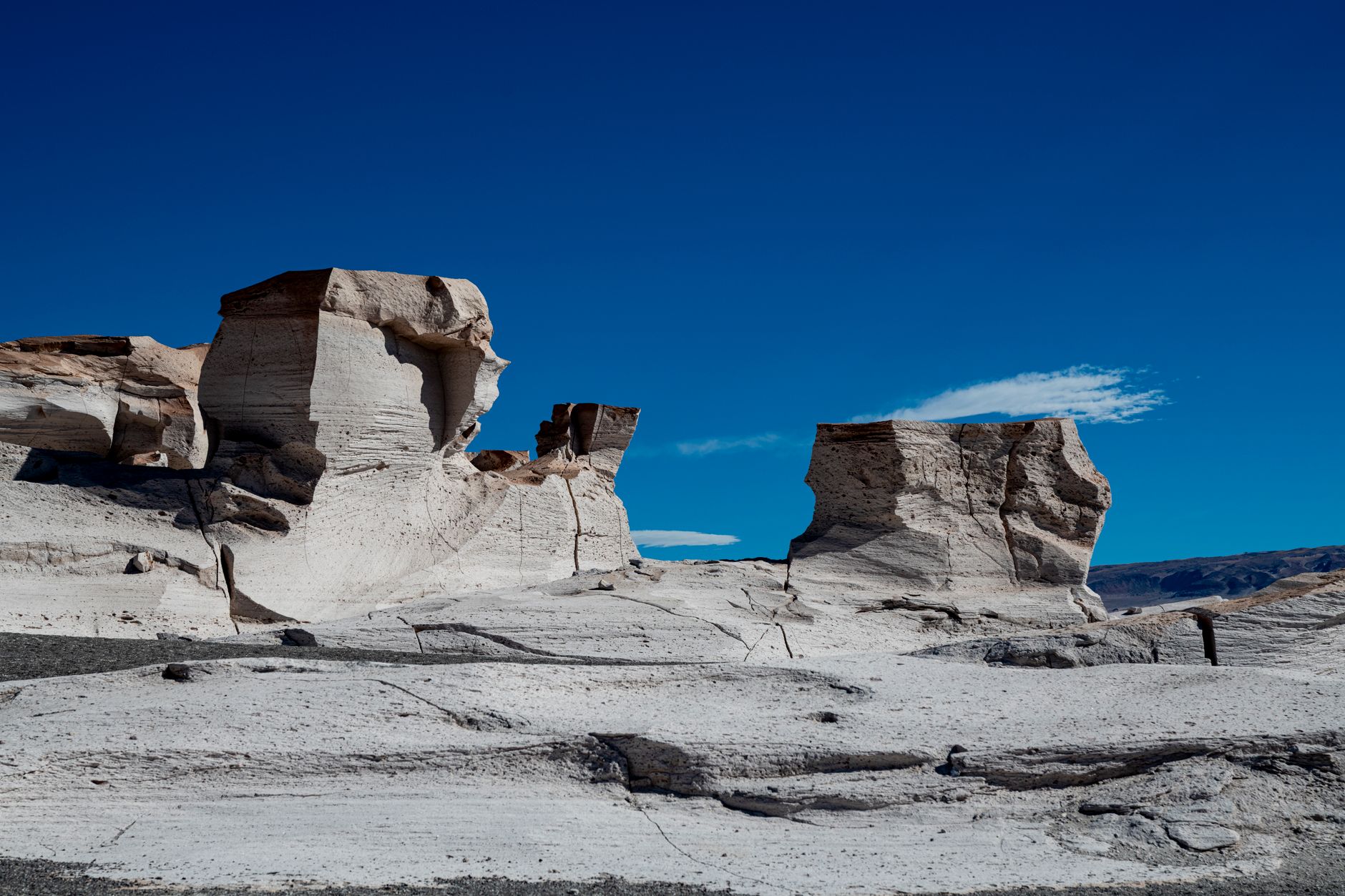 Pale chalk rock formations rising from flat sand in Egypt's White Desert national park