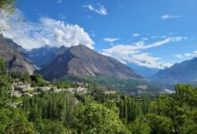 Wide view of a dramatic mountain valley in northern Pakistan with snow-capped peaks in the background