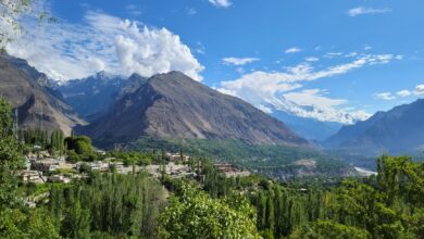 Wide view of a dramatic mountain valley in northern Pakistan with snow-capped peaks in the background