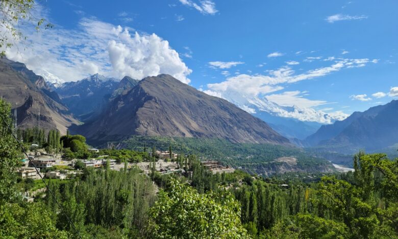 Wide view of a dramatic mountain valley in northern Pakistan with snow-capped peaks in the background