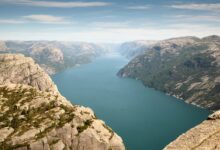 Dramatic limestone cliffs rising vertically from calm blue water in a narrow coastal inlet