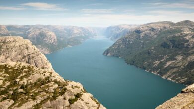 Dramatic limestone cliffs rising vertically from calm blue water in a narrow coastal inlet