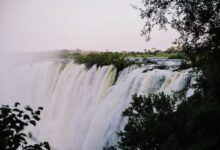 Wide view of the Zambezi River with green floodplains and distant escarpment under open sky