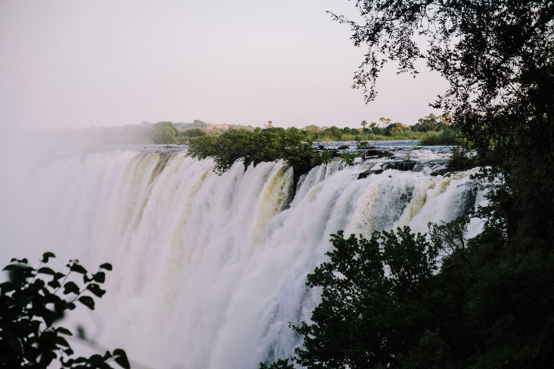 Wide view of the Zambezi River with green floodplains and distant escarpment under open sky