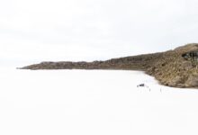 Wide view of a white salt flat stretching to the horizon under a pale blue sky