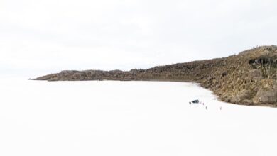Wide view of a white salt flat stretching to the horizon under a pale blue sky
