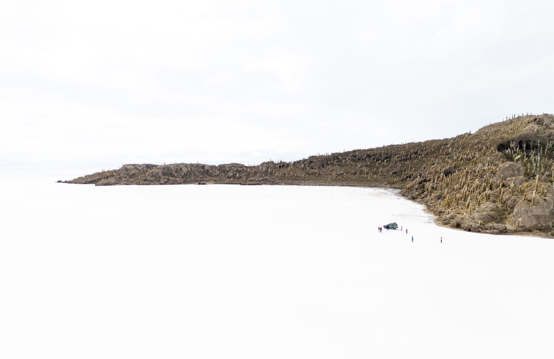 Wide view of a white salt flat stretching to the horizon under a pale blue sky