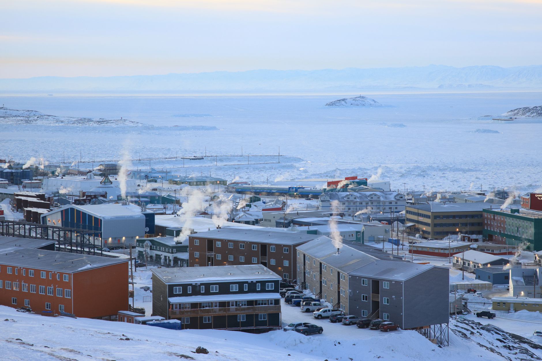 Colorful buildings of Longyearbyen settlement surrounded by snow-covered Arctic mountains