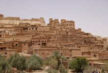 Ancient mud-brick kasbah in the Draa Valley with palm trees and rocky desert in the background