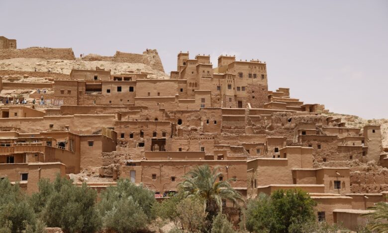 Ancient mud-brick kasbah in the Draa Valley with palm trees and rocky desert in the background