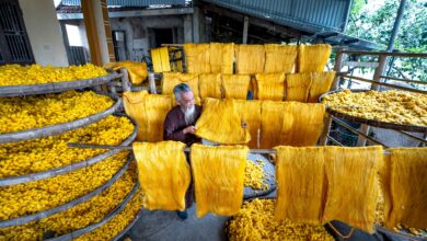 A craftsman weaving colorful ikat silk fabric on a traditional loom in a Central Asian workshop