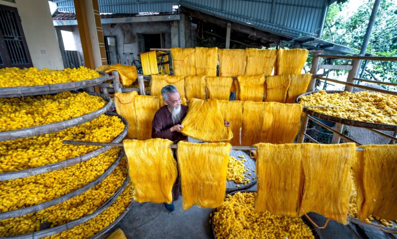 A craftsman weaving colorful ikat silk fabric on a traditional loom in a Central Asian workshop