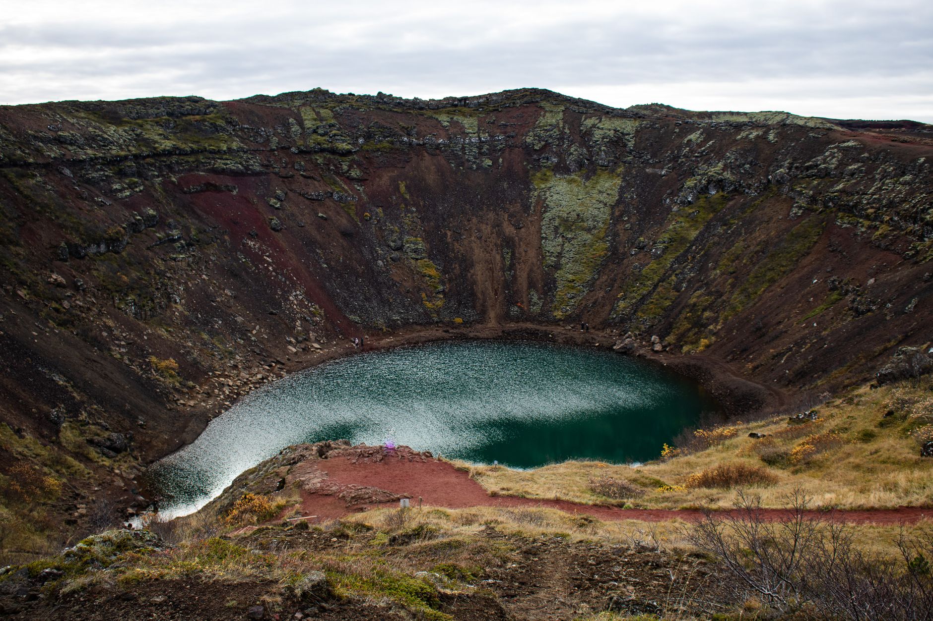 Turquoise volcanic crater lake surrounded by steep Andean caldera walls at high altitude