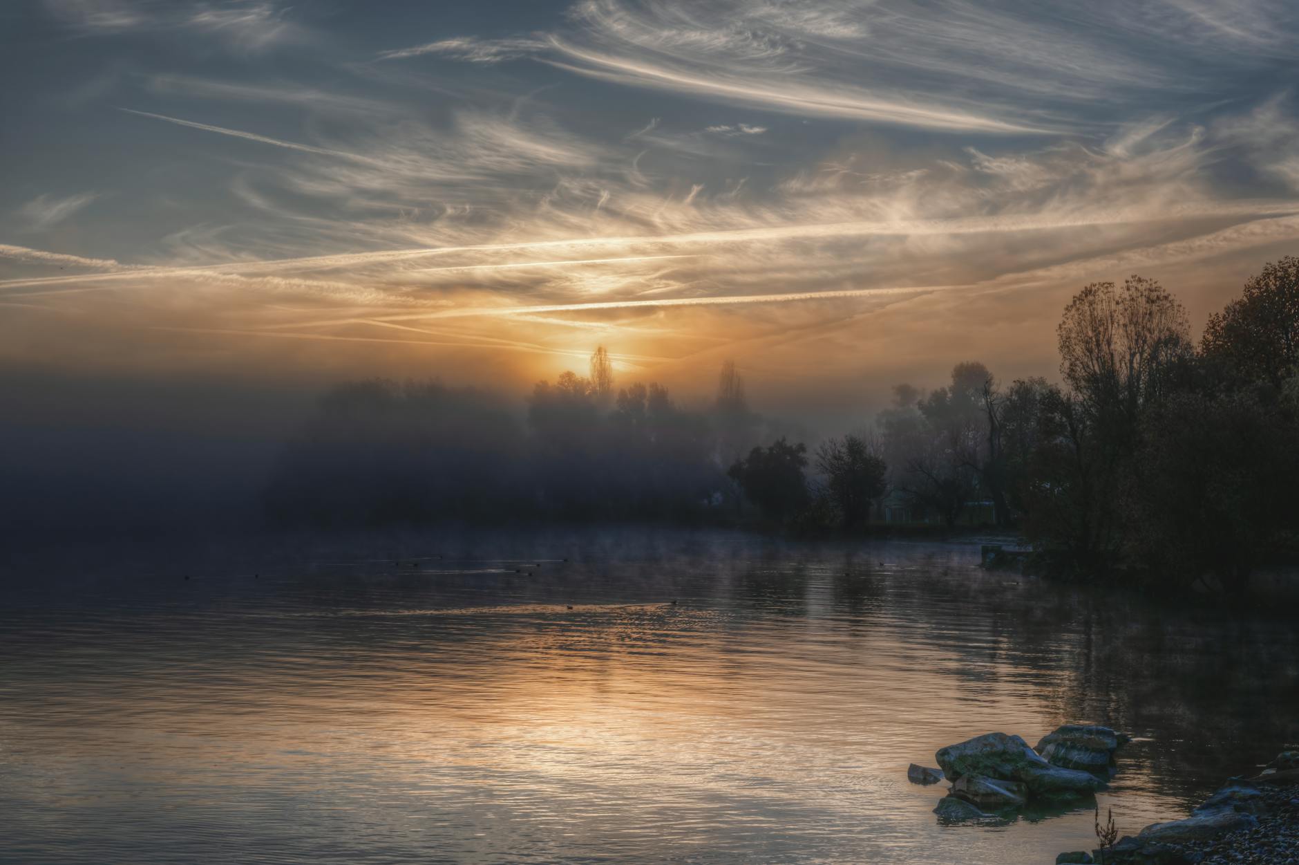 Misty lake at dawn with calm water and distant hills, evoking the quiet atmosphere of Inle Lake in Myanmar