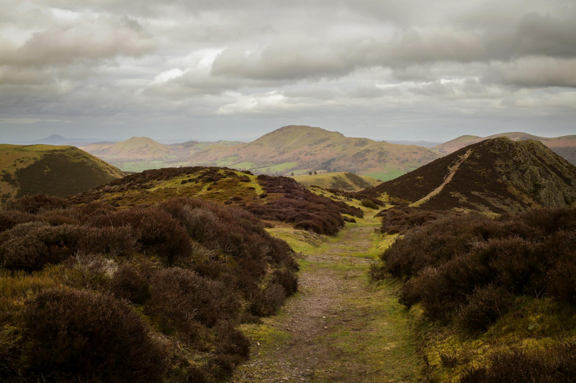 Trekker walking across open highland moorland with mountain peaks in the background