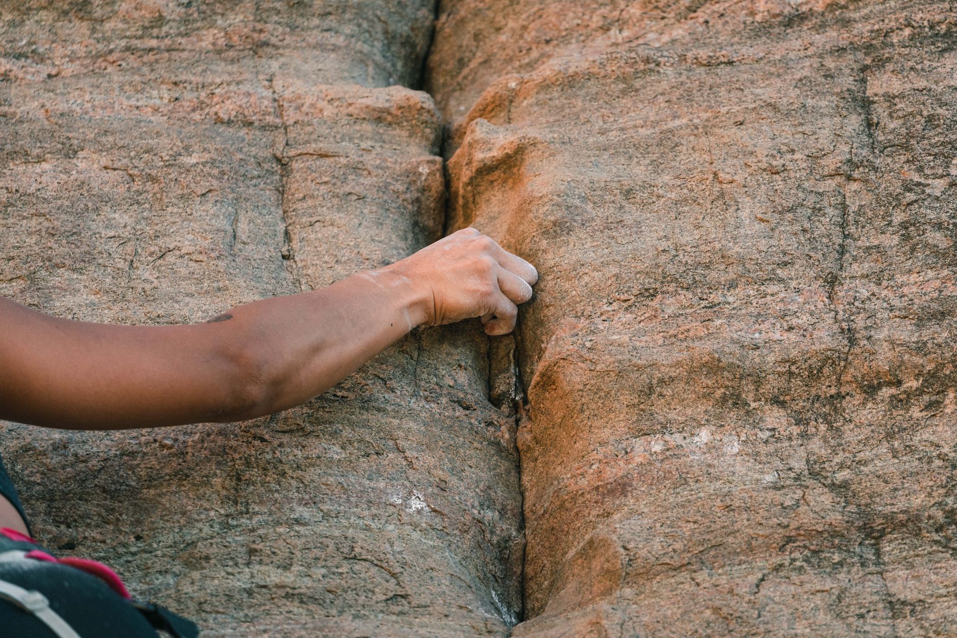 Climber ascending a vertical rock face with dramatic landscape in the background