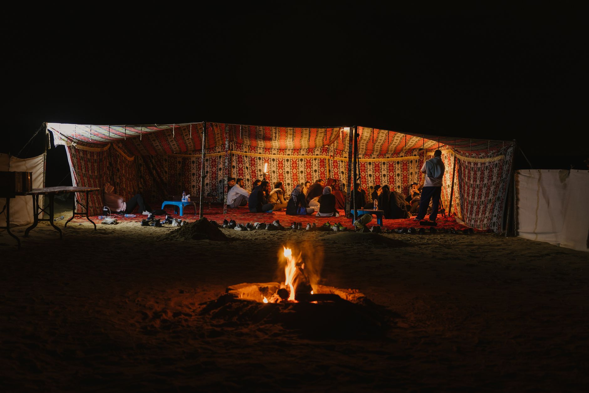Campfire and tents set up on sand beneath a clear starlit sky in the Sahara