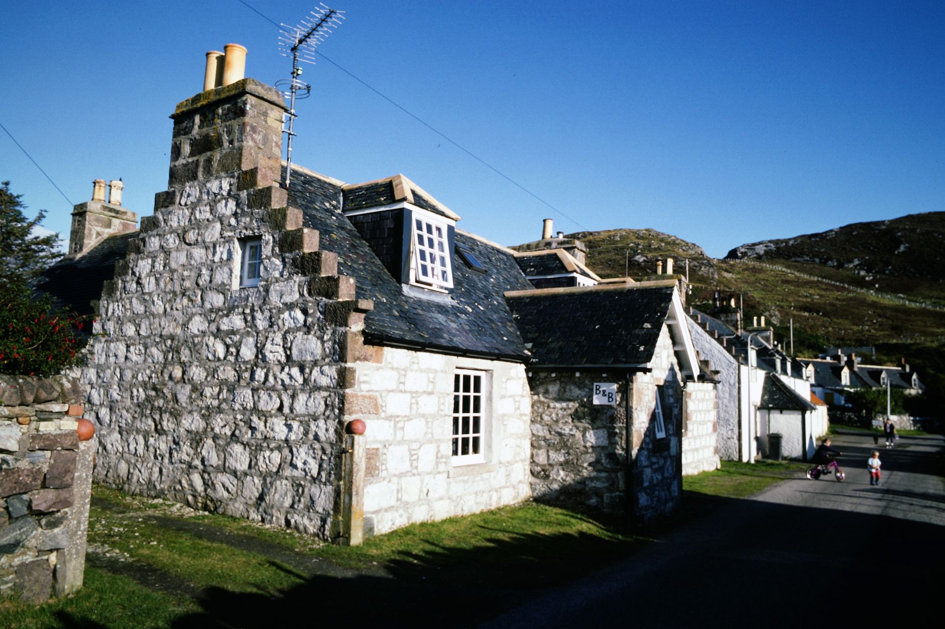 Traditional stone buildings in a highland village surrounded by green slopes