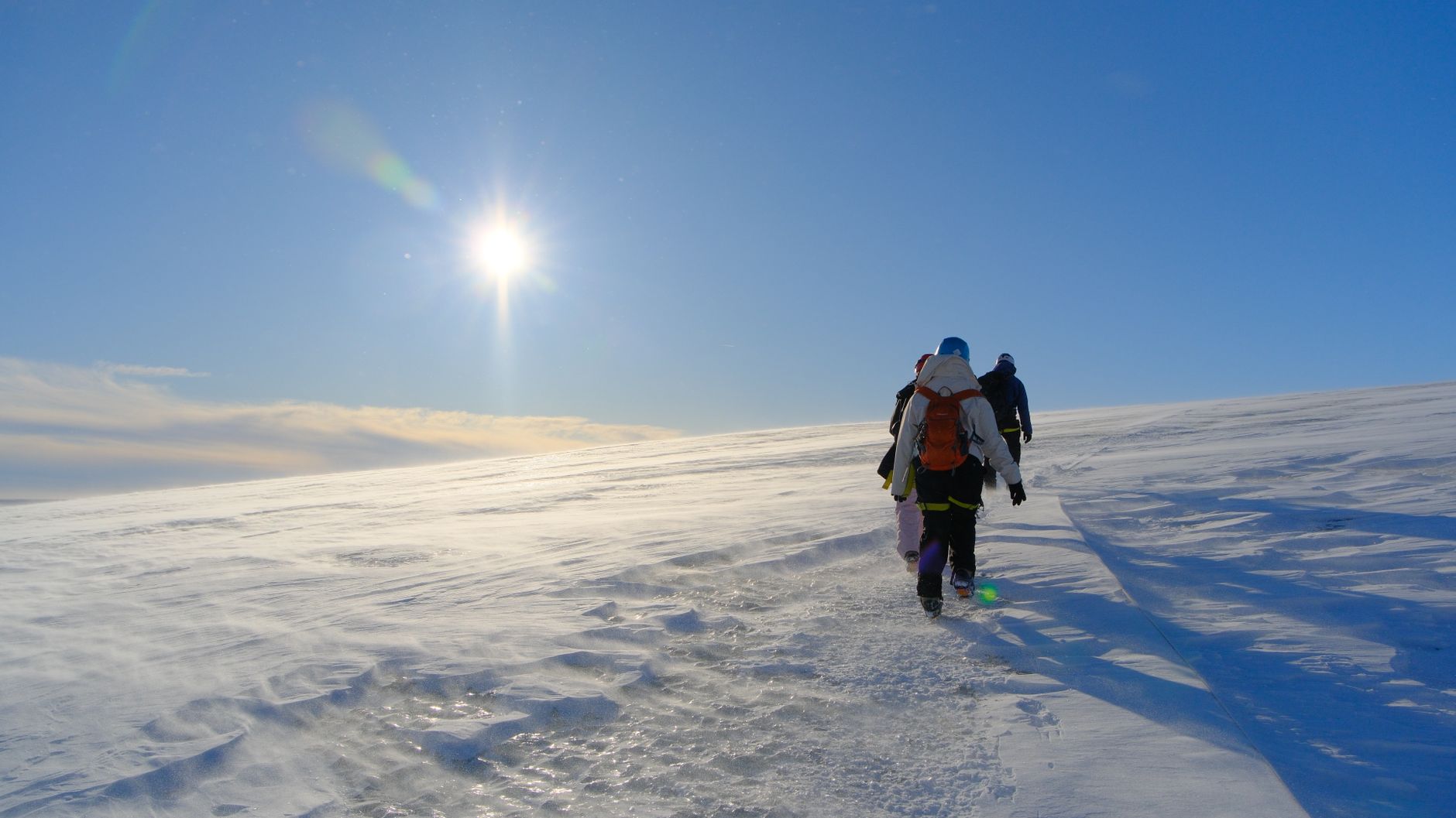 Hiker walking across a retreating glacier with blue ice formations in the Arctic