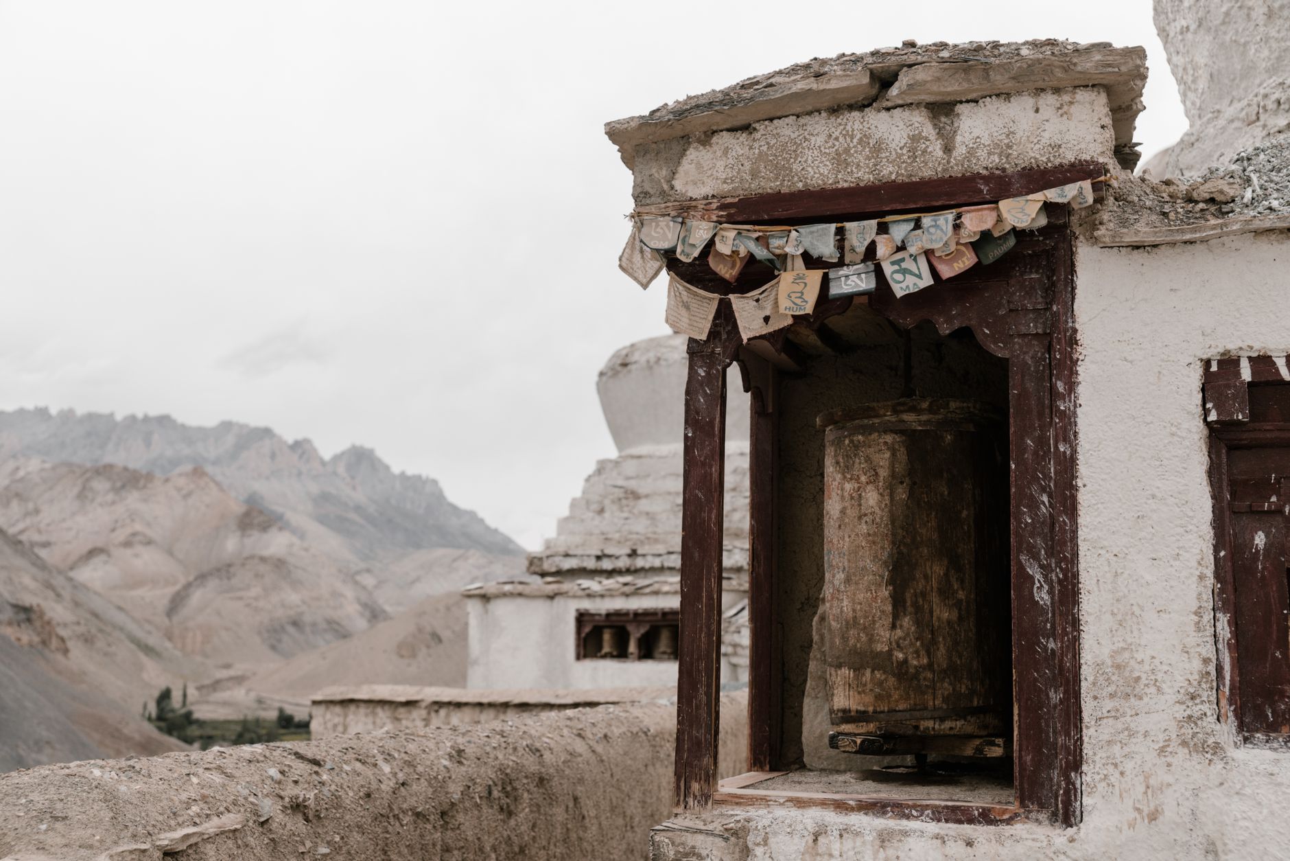 Ancient whitewashed monastery walls with colorful Buddhist prayer flags in a remote mountain setting