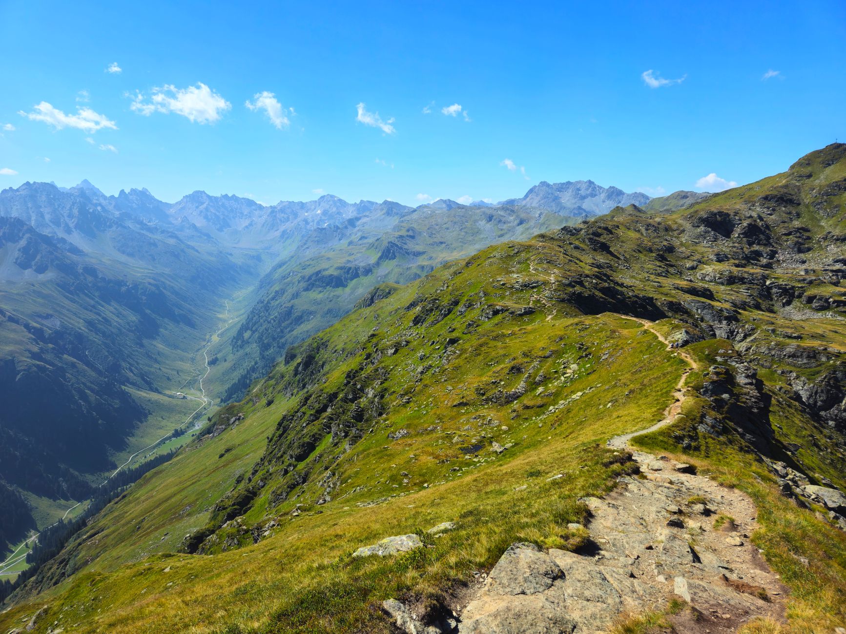 Hiker on a rocky mountain trail with dramatic glacier views and open sky overhead