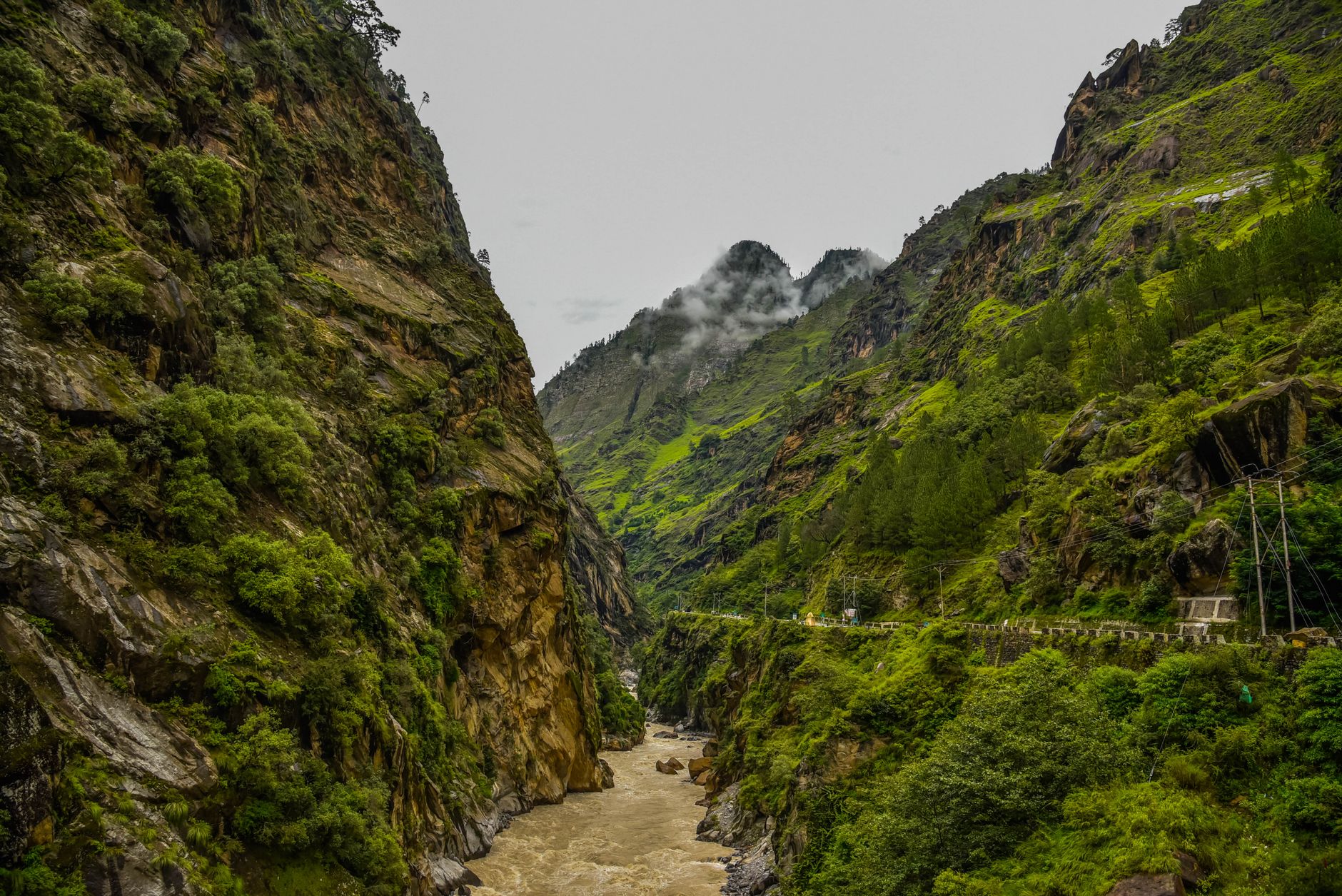 Narrow winding road cutting through a dramatic mountain gorge with steep rock walls