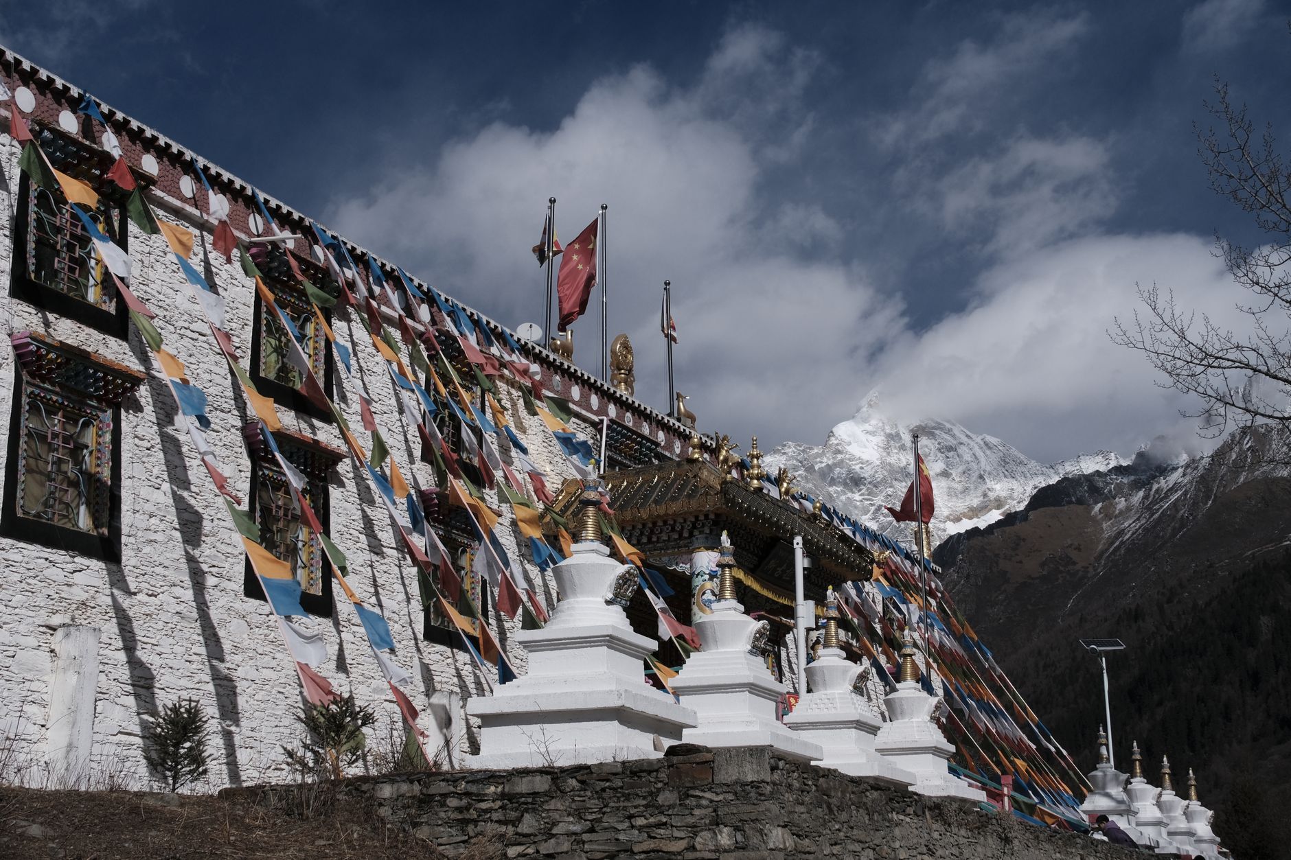 A Tibetan Buddhist monastery set against a backdrop of snow-capped mountain peaks