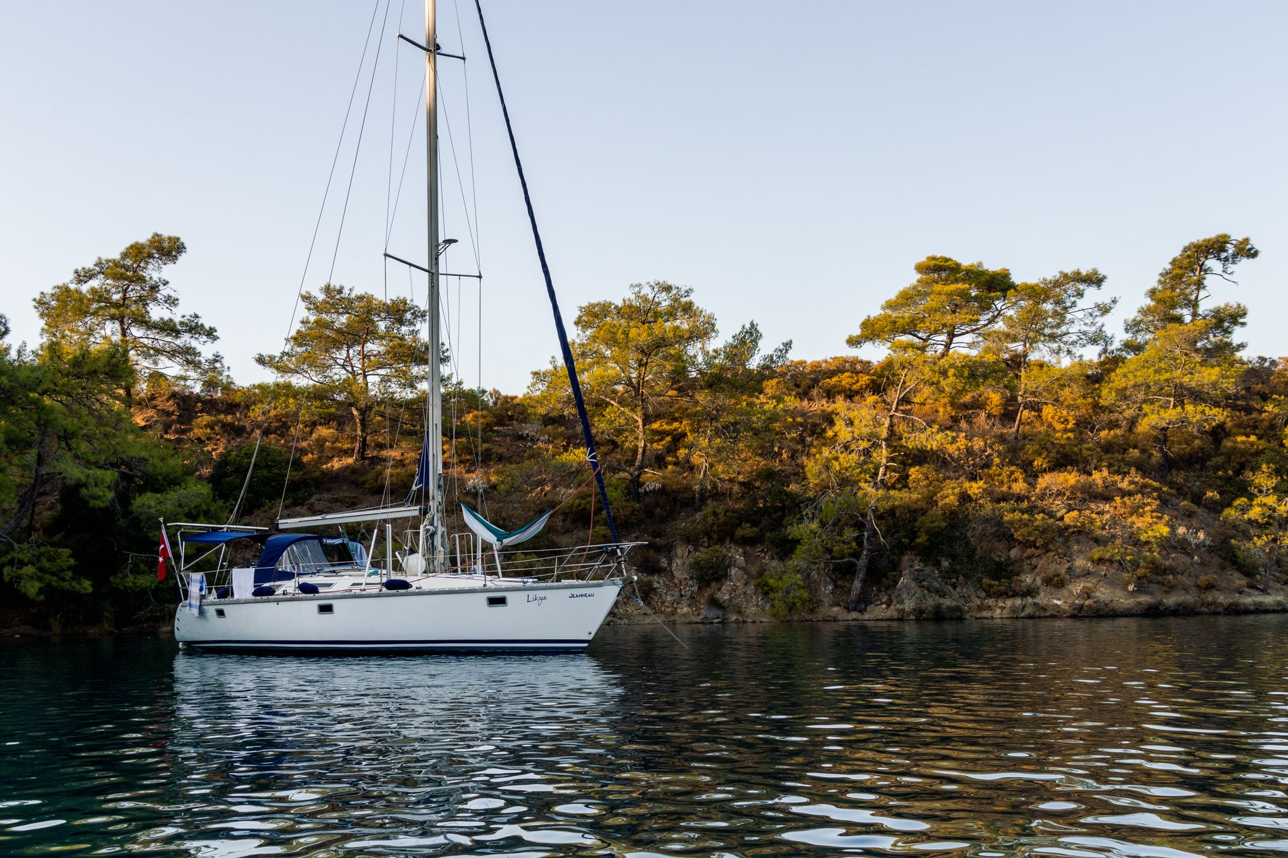 A sailboat anchored in a clear blue cove in the Ionian Sea