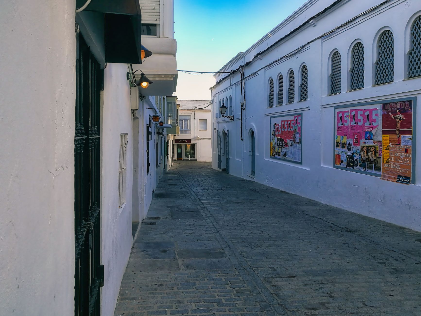 Narrow whitewashed alley in a North African medina with blue doors and hanging lanterns
