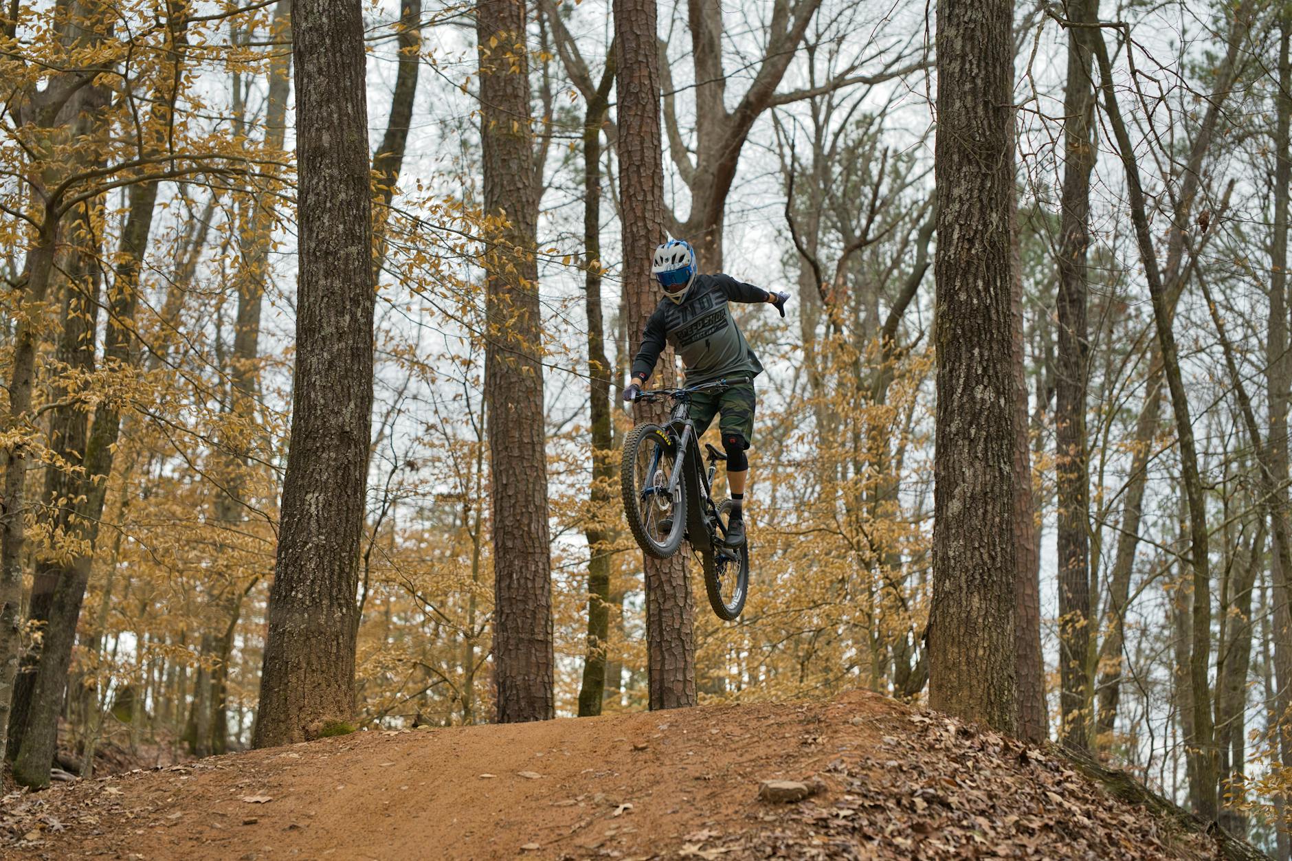 Mountain biker navigating a loose gravel trail on a steep forested hillside