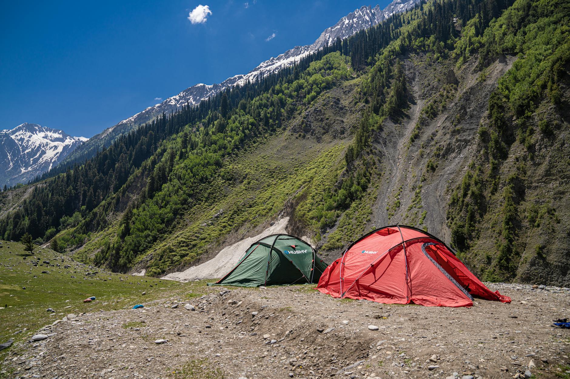 Camping tent pitched at high altitude with mountain landscape visible at dusk