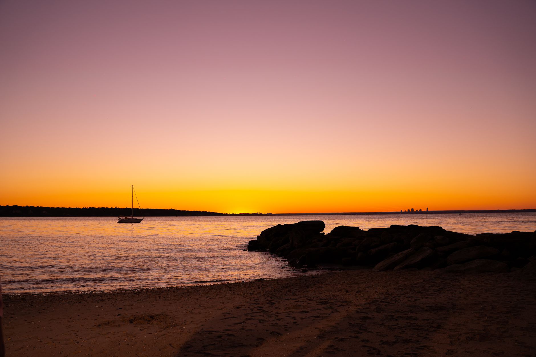 Quiet waterfront beach at sunset with calm sea and warm orange sky