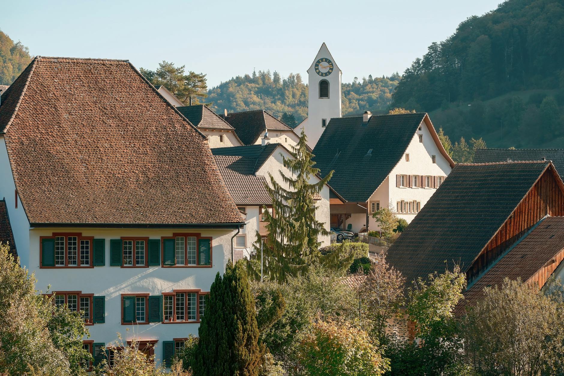 A small alpine village surrounded by autumn-colored trees and mountain slopes