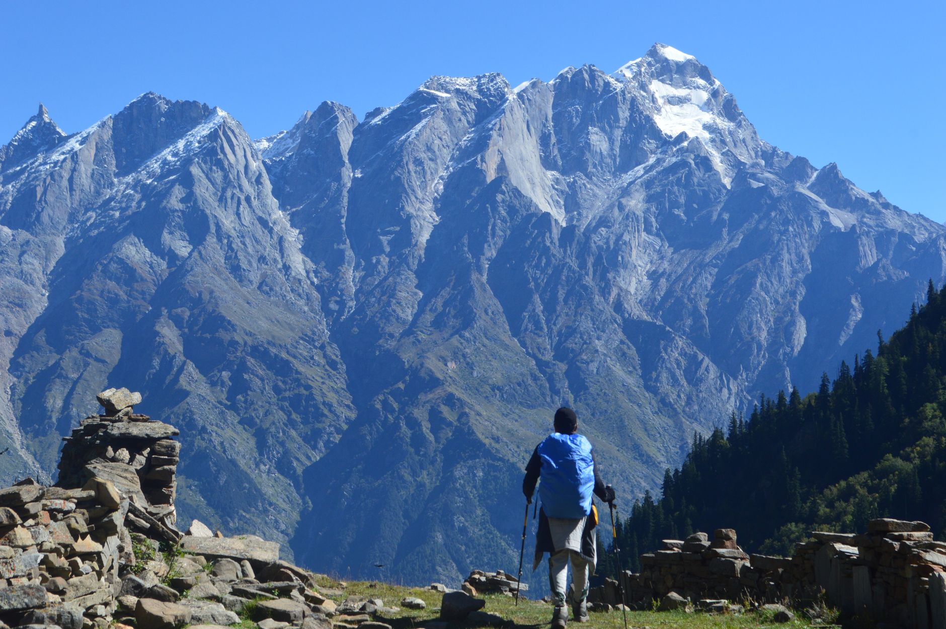 A trekker hiking along a rocky mountain trail with open highland landscape ahead