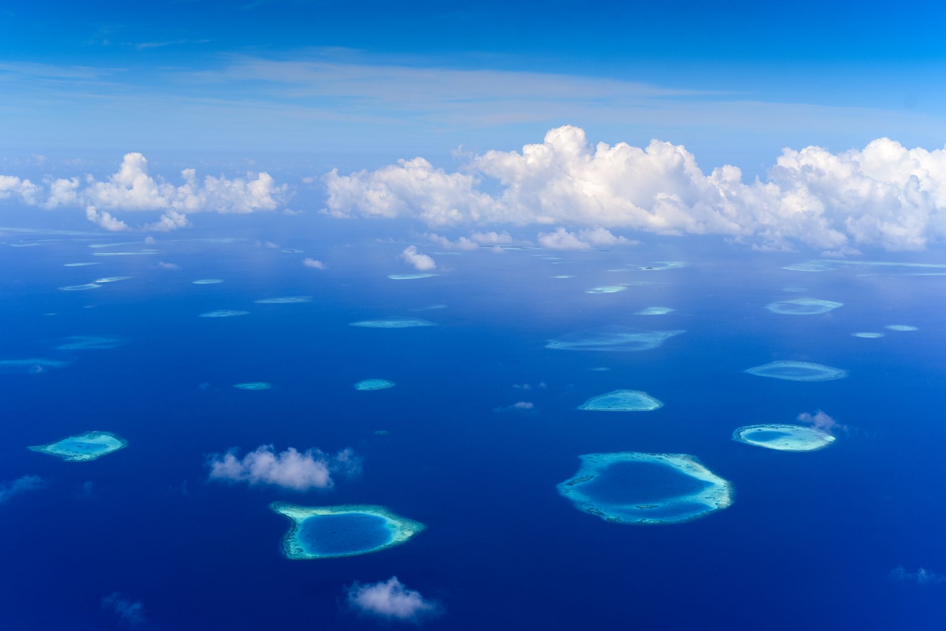 Aerial view of a remote tropical island surrounded by turquoise reef waters