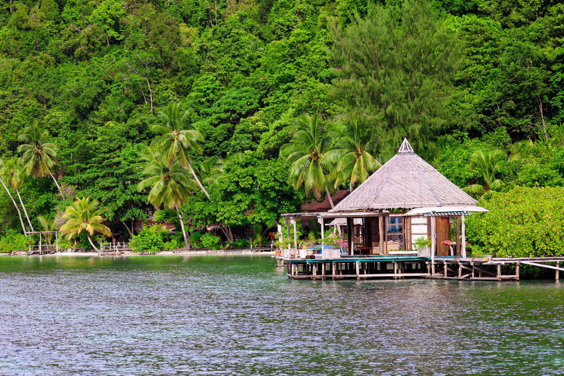 Wooden overwater bungalow on a remote tropical island surrounded by calm blue water