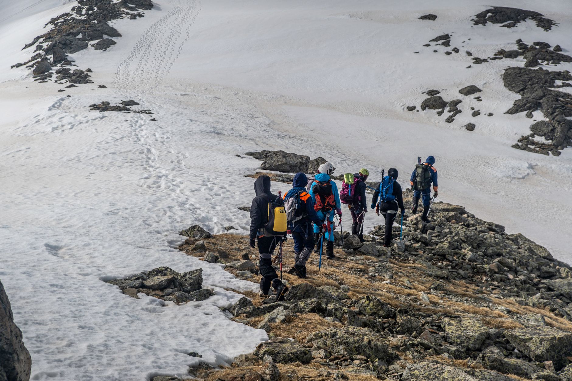 Hiker crossing a high mountain pass with glacial lake visible below