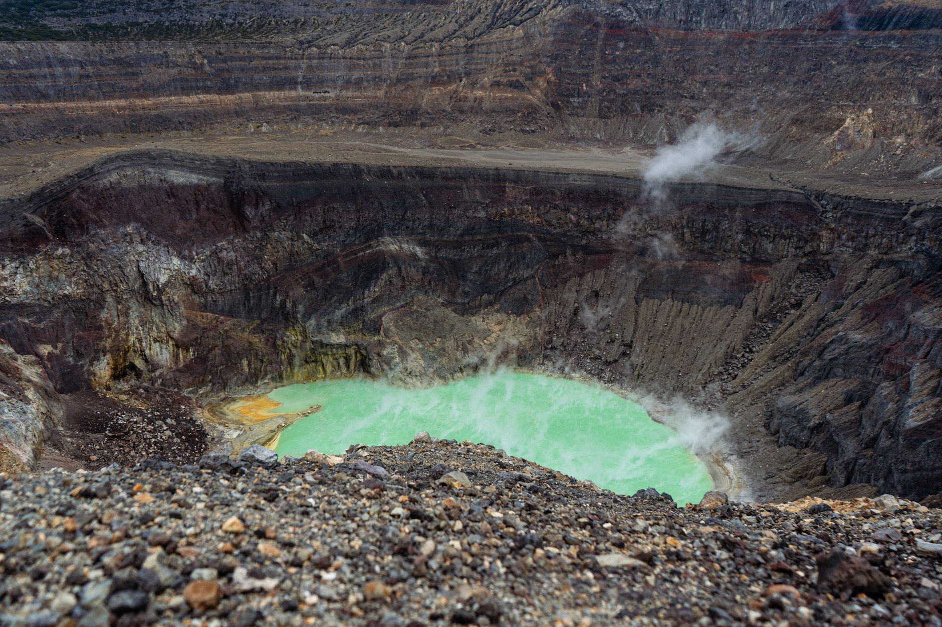 A still crater lake surrounded by forest near a volcanic summit
