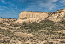 Towering sandstone rock formations rising from a Saharan desert landscape under a clear blue sky
